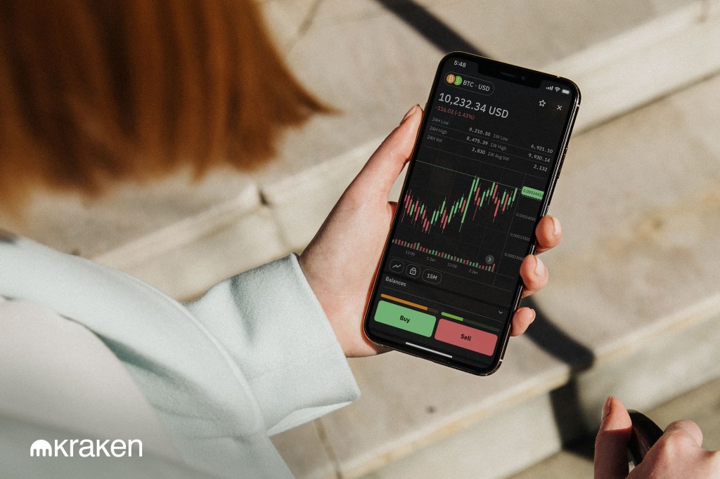 Woman holding mobile phone, buying crypto in the Kraken mobile app