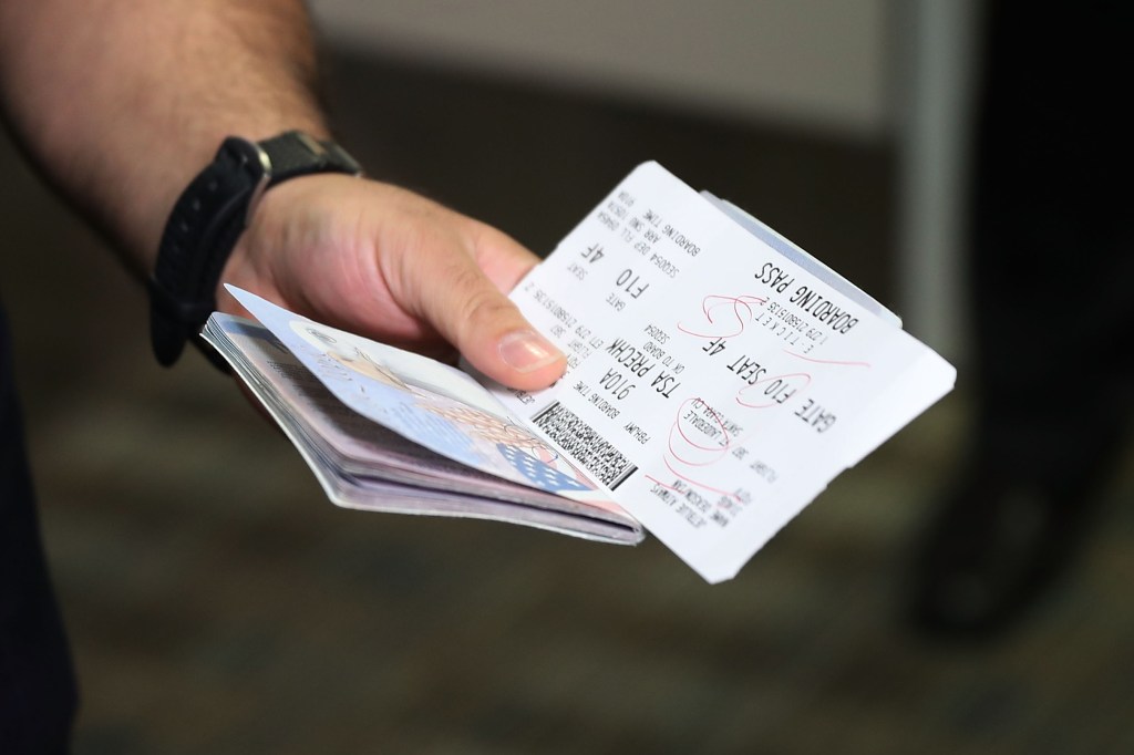 A man is holding a passport and flight ticket,