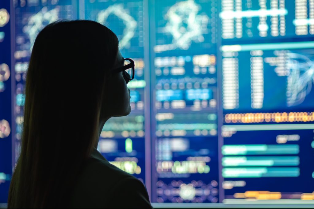 The businesswoman in glasses standing near the display looking at numbers and data