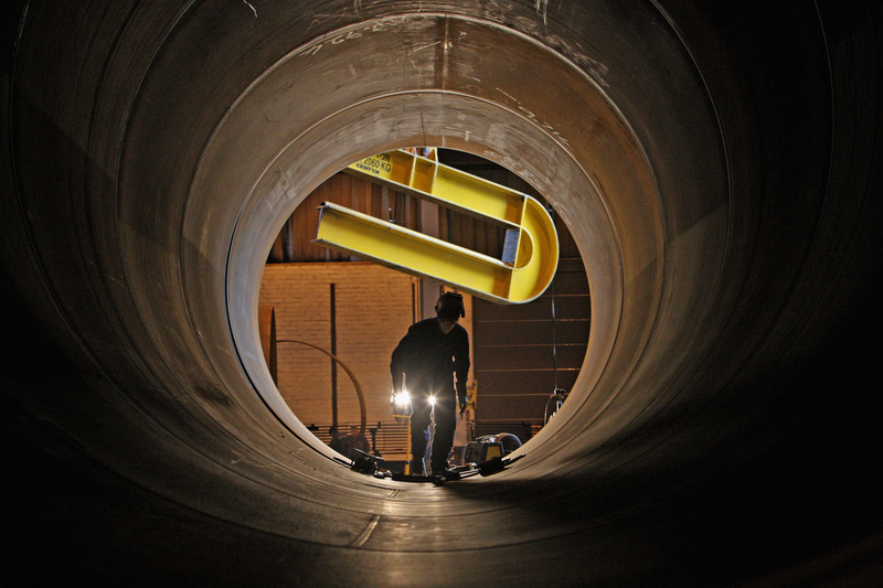 Welders work on tower sections of a wind turbine.