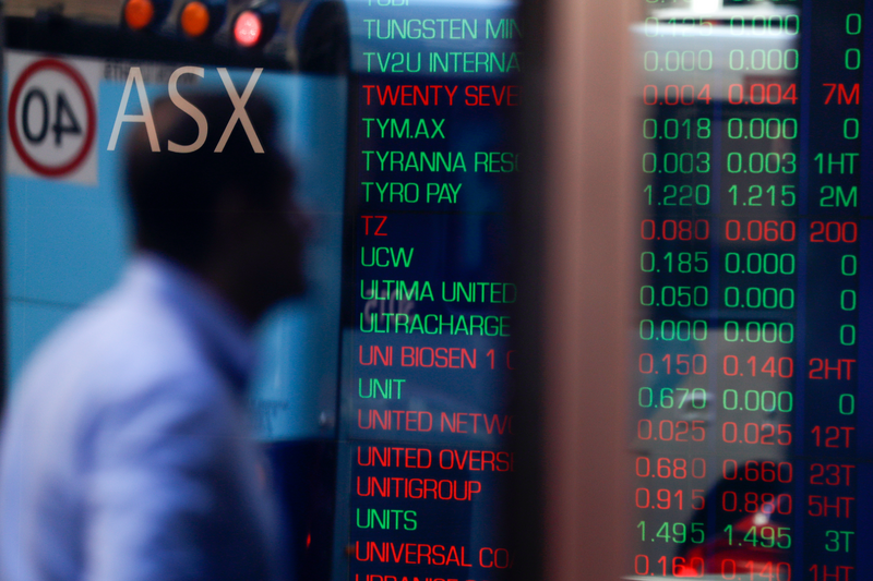 A reflection of a man is seen as an electronic board displays stock information at the Australian Securities Exchange.