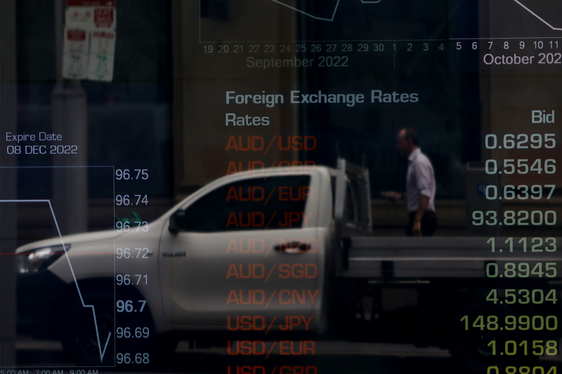 A pedestrian is reflected in a window as electronic boards display stock information at the Australian Securities Exchange