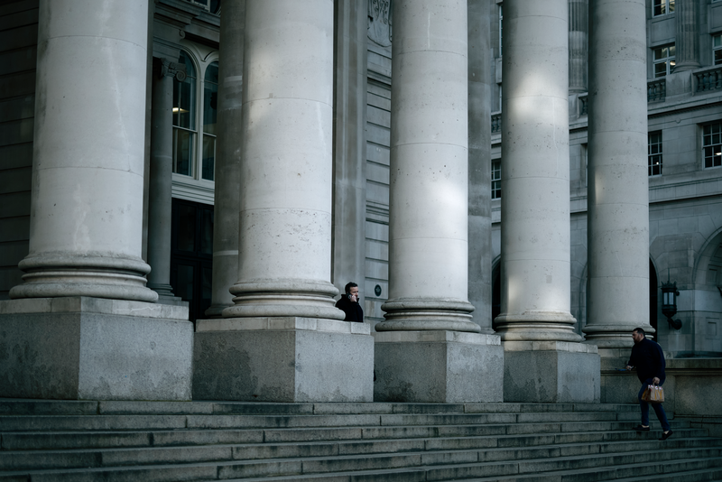 A man makes a call while standing on the stairs of the London Stock Exchange