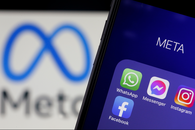 The logos of applications, WhatsApp, Messenger, Instagram and facebook belonging to the company Meta are displayed on the screen of an iPhone in front of a Meta logo