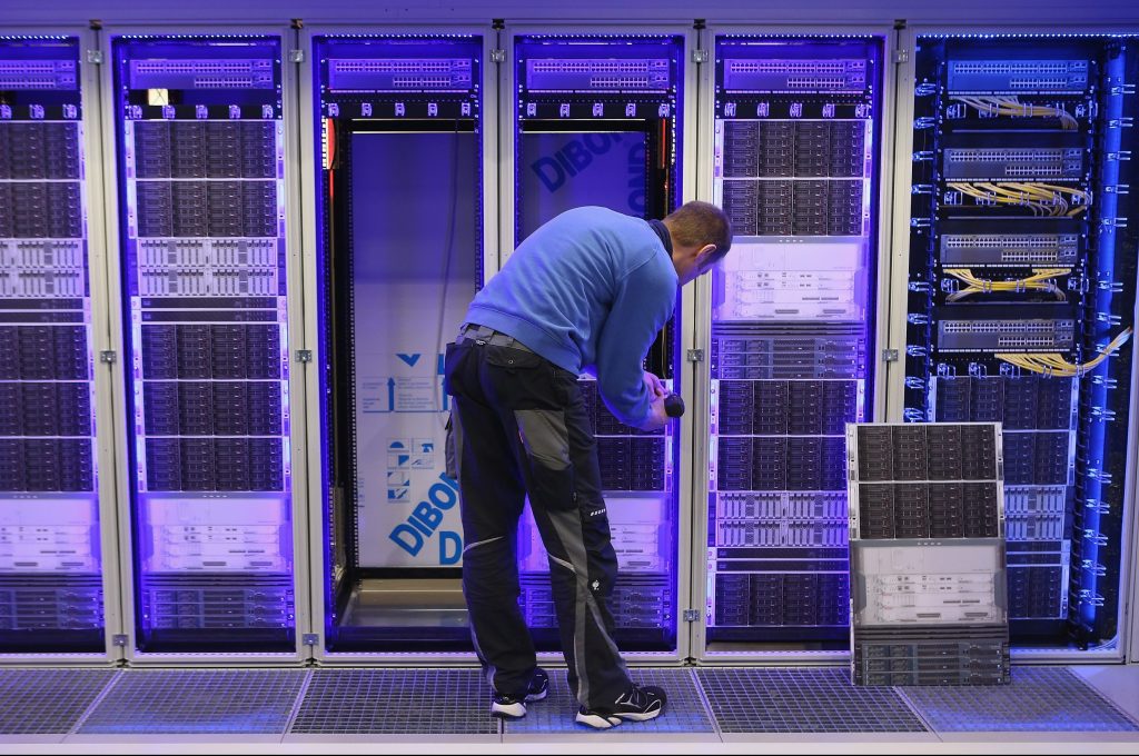Image of an electronic storage center and a man working on some wiring.