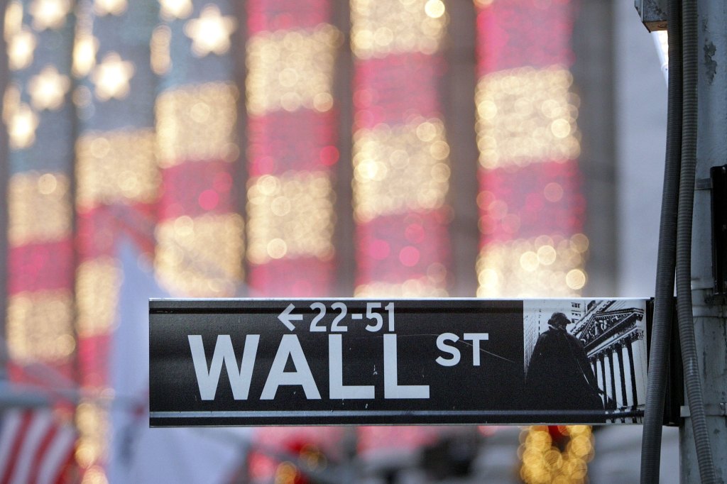 Wall Street sign is shown with images of the American flag behind it.