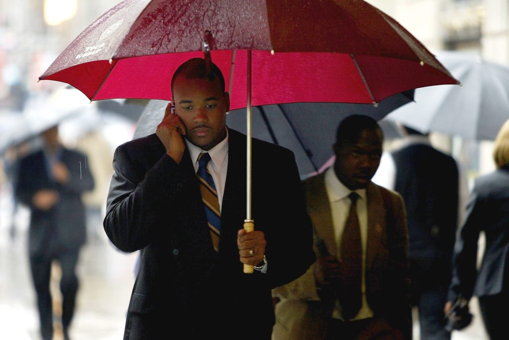 Man holding an umbrella and a phone to his ear.