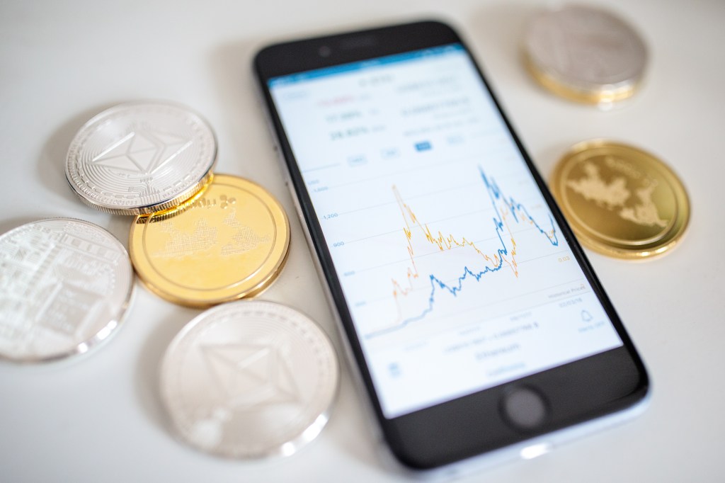 Image of some crypto coins lying next to a mobile phone.