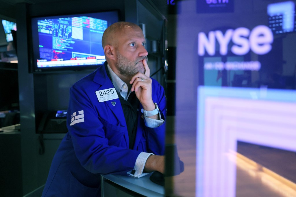 Image of a man sitting inside the New York Stock Exchange, with "NYSE" visible as signage near him.