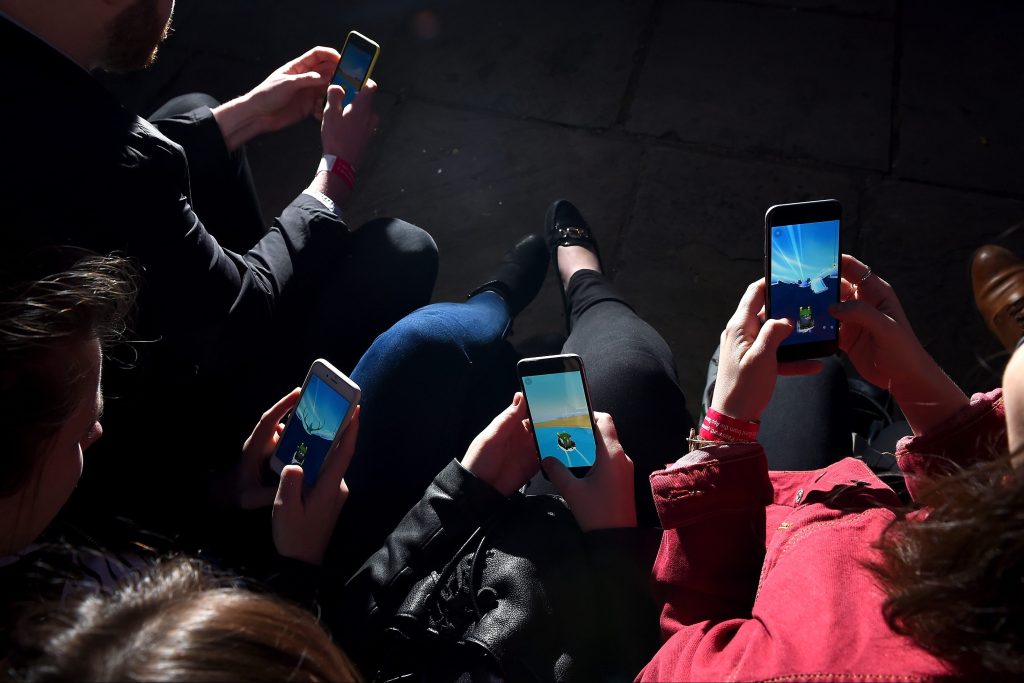 Image of a group of mobile phones in people's hands.