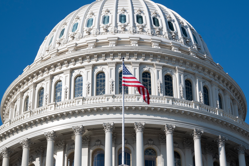 An American flag flies outside the U.S. Capitol building on a clear.