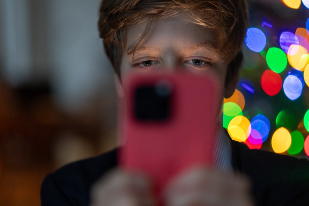 A 12-year-old boy looks at an iPhone screen.