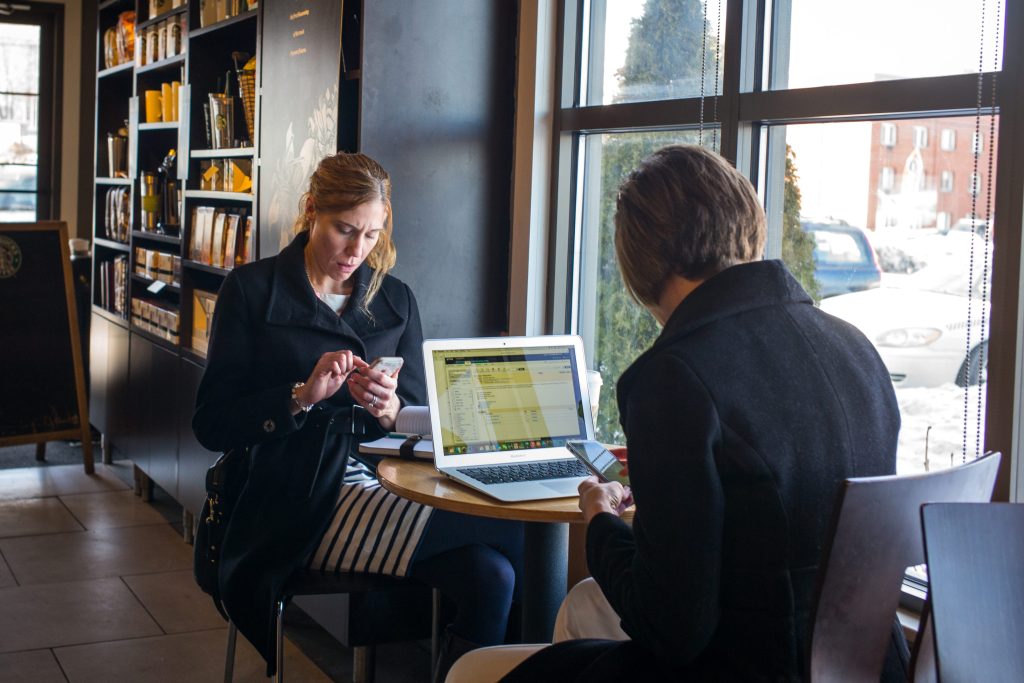 Image of two people working on their laptops at a coffeeshop.