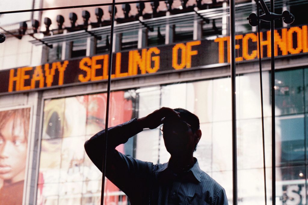 Man stands in front of digital sign saying (in part) "Selling of Technology"