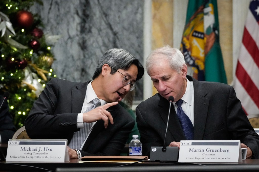 Image of Michael Hsu (OCC) and Michael Gruenberg (FDIC) chatting at a conference table.