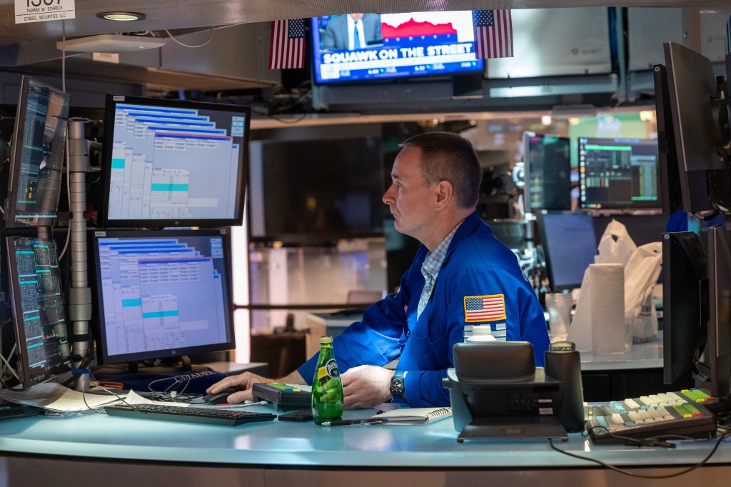 Image of a broker watching order flow on computer screens.