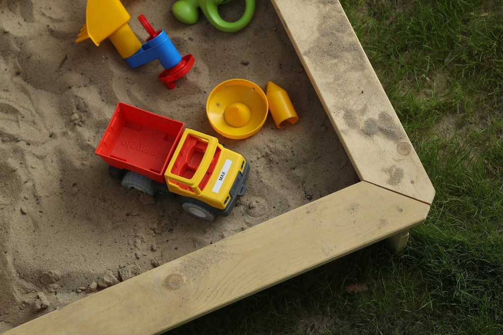 Image of a sandbox with a couple of kids' toys in it.