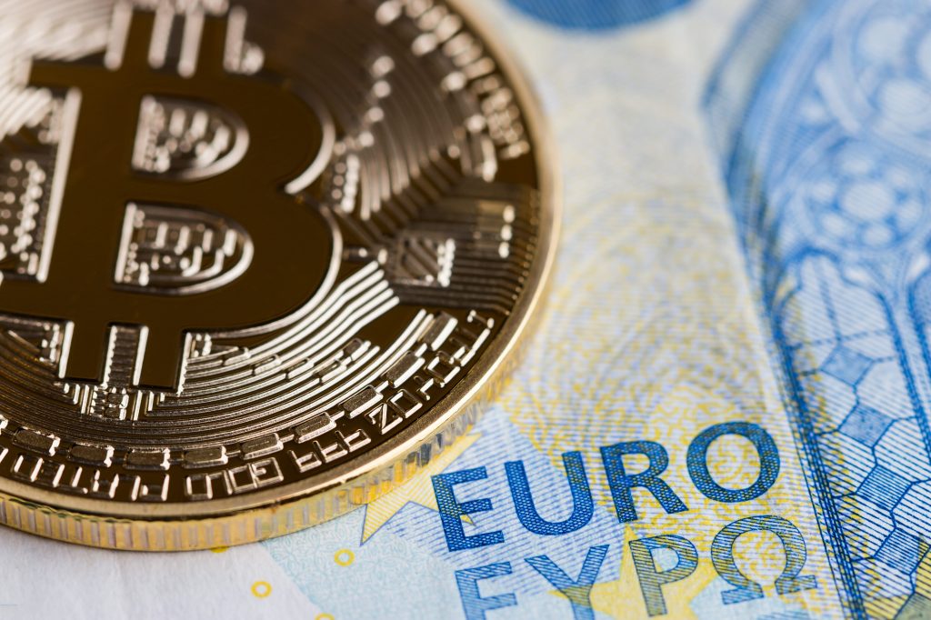 A Bitcoin is laying on a Euro note.