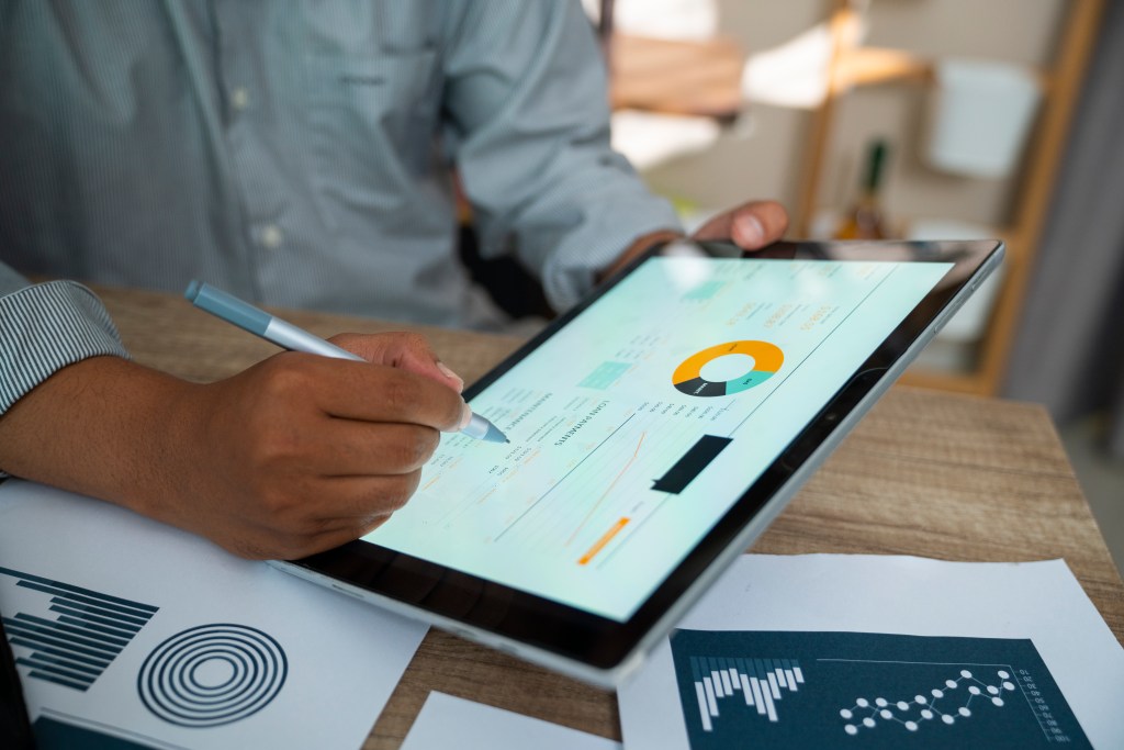 man analyzing statistical business report on tablet pc