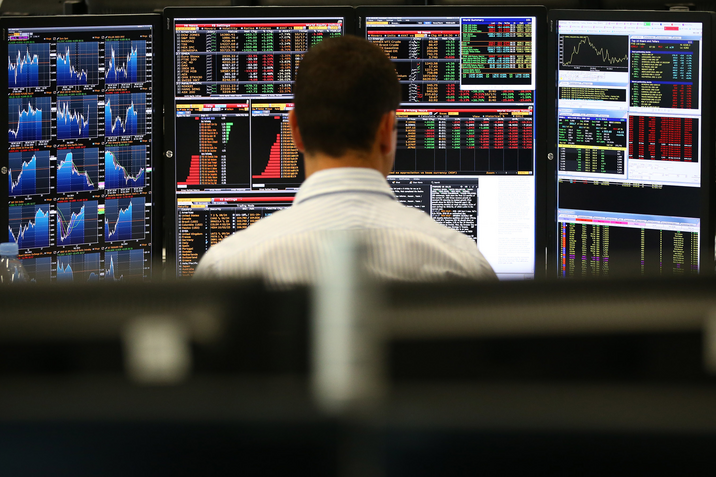 An employee views trading screens at the offices of Panmure Gordon and Co.