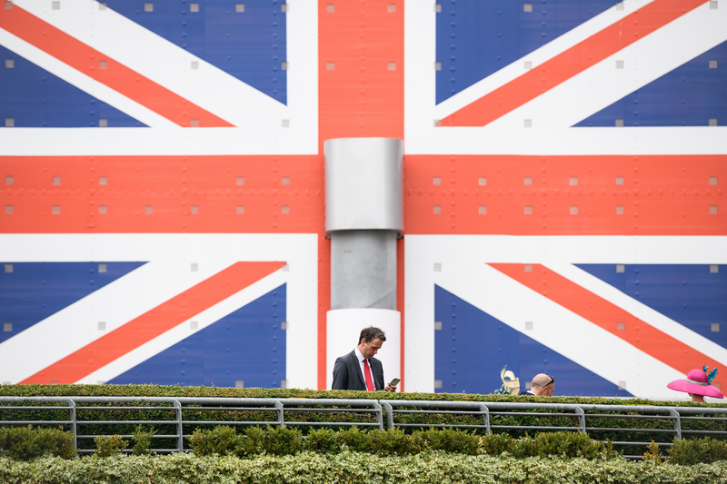 A man checks his phone as he stands next to a gaint Union flag.