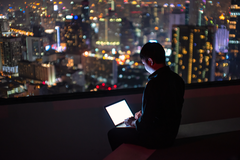 A man is working on Laptop notebook monitor white screen rooftop backdrop city view.