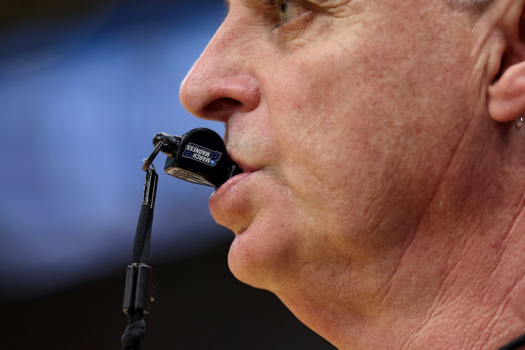 image of a referee with a whistle in his mouth.