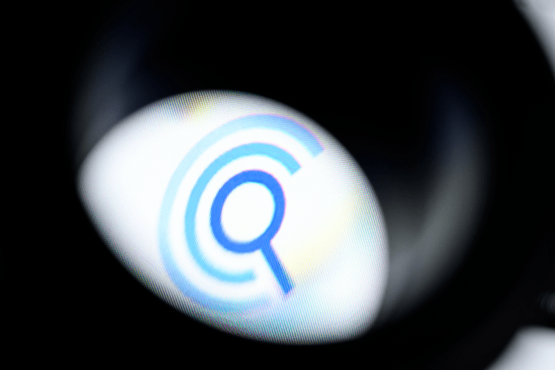 The logo of the data broker company Clearview.AI is seen through a magnifying loupe as it is displayed on a screen