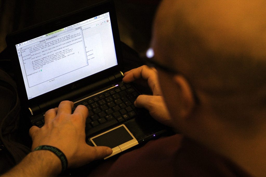 Image of a man looking at lines of code on a laptop.