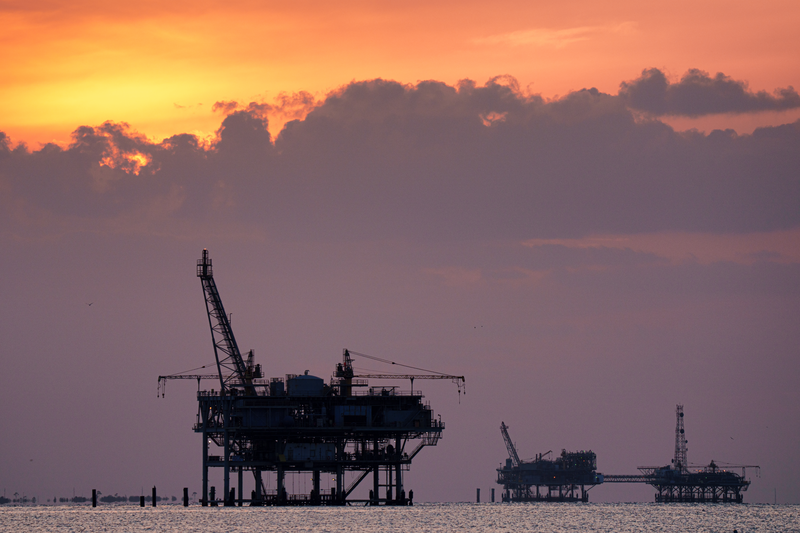 Offshore gas rigs are silhouetted against the setting sun on May 10, 2024, near Fort Morgan, AL.