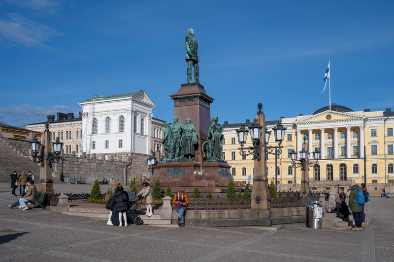 View of Senate square with people and tourists enjoying the sunny afternoon in Helsinki, Finland.