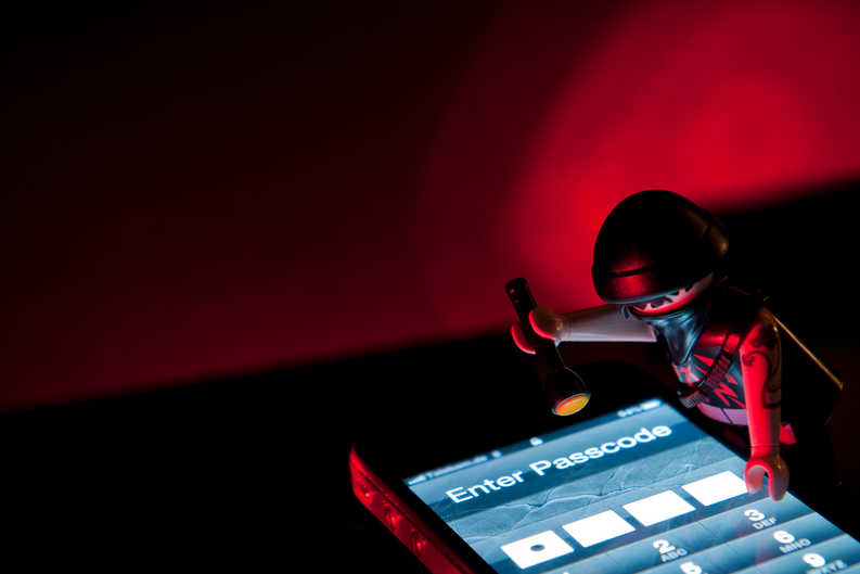 Playmobil Hacker dressed in dark clothing with torch about to steal information from mobile