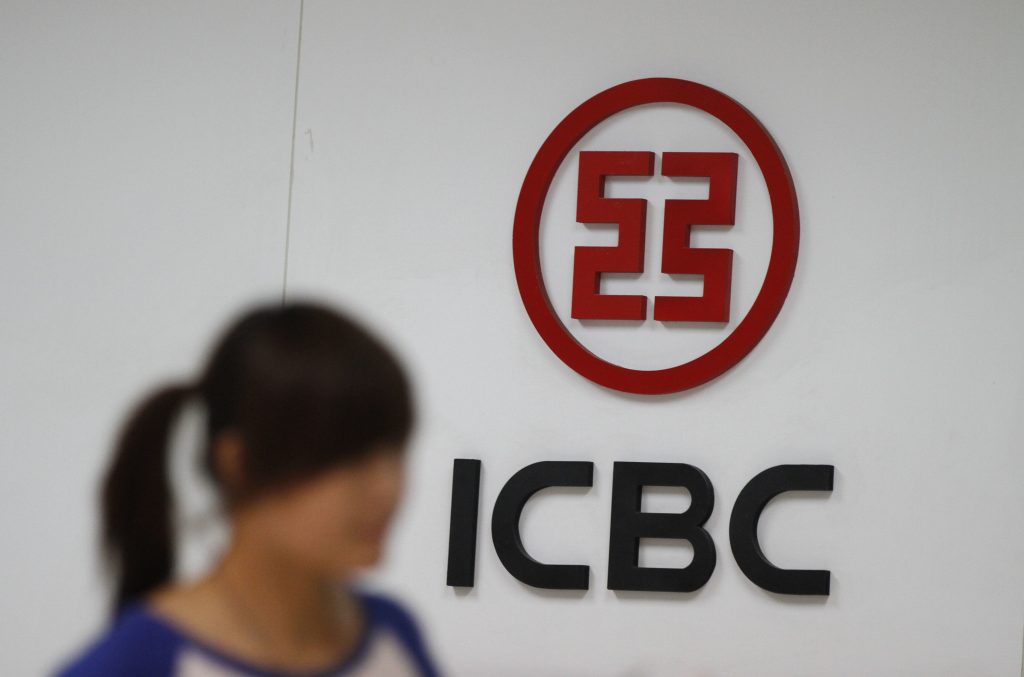 A woman walks past a branch of Image of a woman walking by the Industrial and Commercial Bank of China.