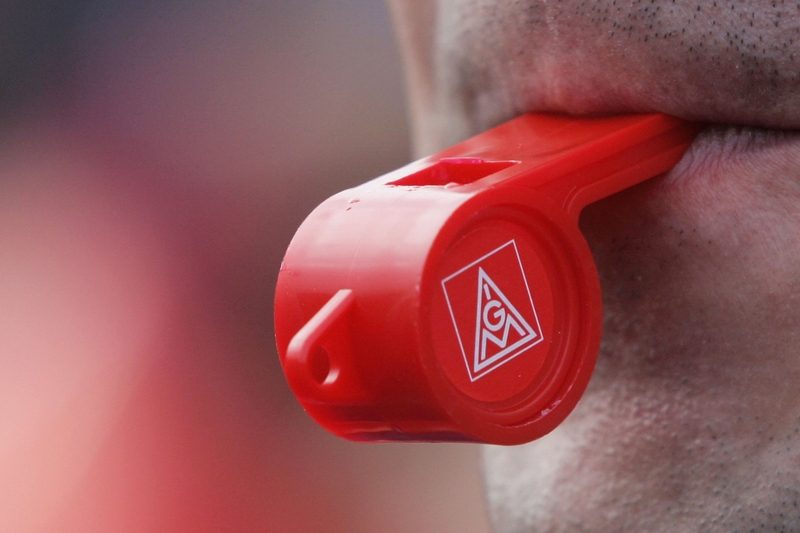 A worker from an engine plant of German carmaker DaimlerChrysler blows a whistle in protest for 5% more pay during a warning strike.