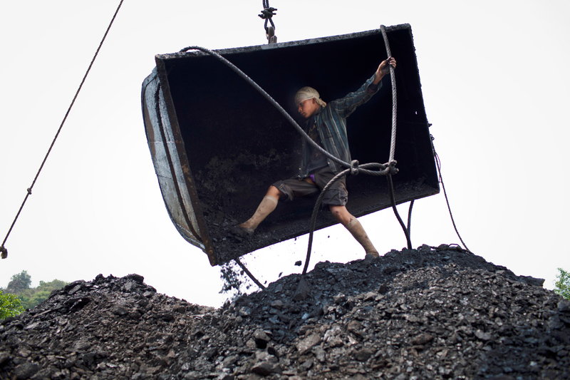 Fourteen-year-old Chhai Lyngdoh, kicks out the coal from a container, as it is emptied onto a heap, after being craned out of a 300ft deep mine shaft, India.