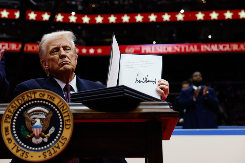 . President Donald Trump holds up an executive order after signing it during an indoor inauguration parade at Capital One Arena on January 20, 2025 in Washington, DC.