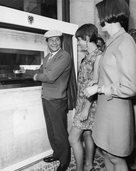 English actor Reg Varney (1916 - 2008) makes the first withdrawal from a Barclaycash machine, at the Enfield branch of Barclays Bank, 27th June 1967. The Enfield Barclaycash is the world's first automatic cash dispensing machine. 